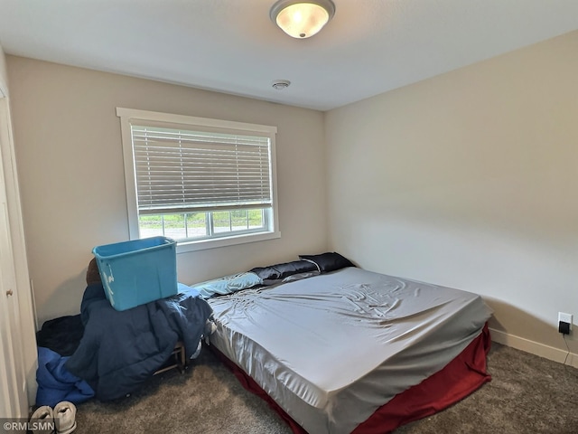 bedroom with dark colored carpet, visible vents, and baseboards