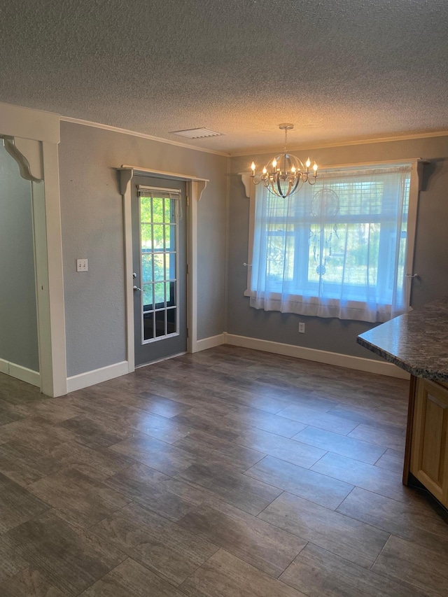 unfurnished dining area featuring crown molding, a textured ceiling, an inviting chandelier, and baseboards