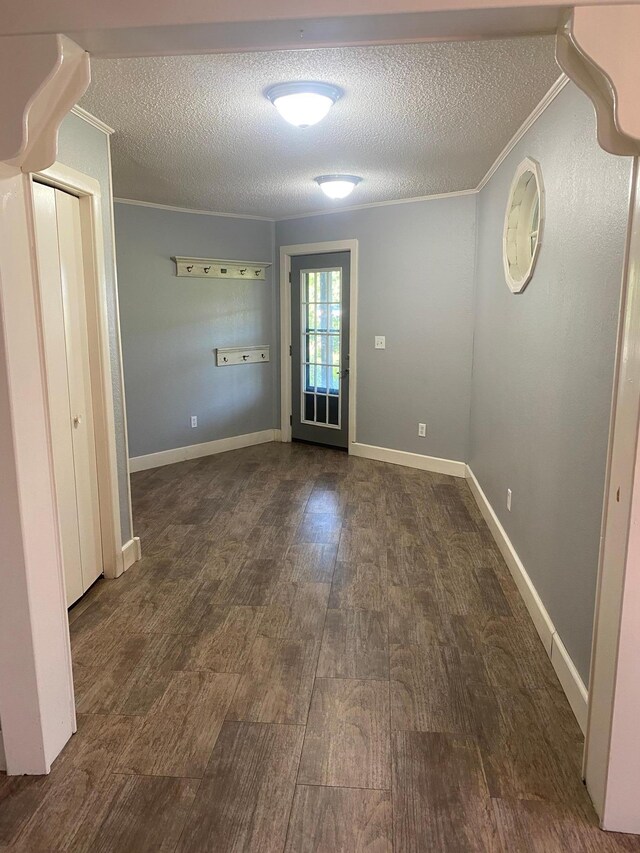 unfurnished room with dark hardwood / wood-style floors, ornamental molding, and a textured ceiling