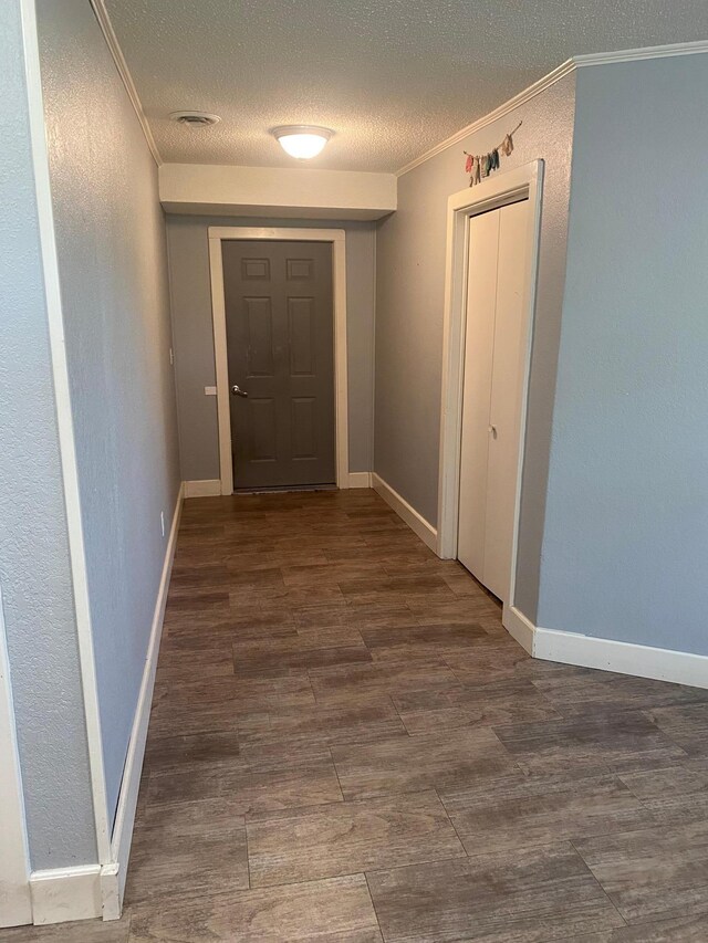 corridor with ornamental molding, a textured ceiling, and dark hardwood / wood-style floors