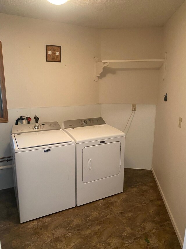 clothes washing area with dark tile patterned floors and washer and dryer