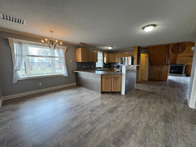 kitchen featuring a peninsula, a chandelier, baseboards, visible vents, and a textured ceiling