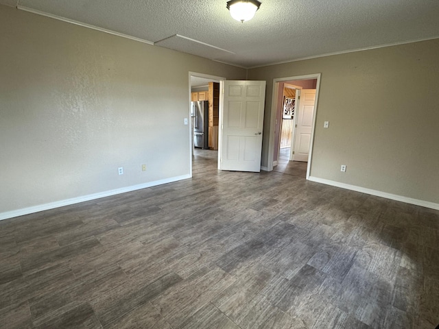 unfurnished bedroom with baseboards, a textured ceiling, dark wood-style floors, and freestanding refrigerator