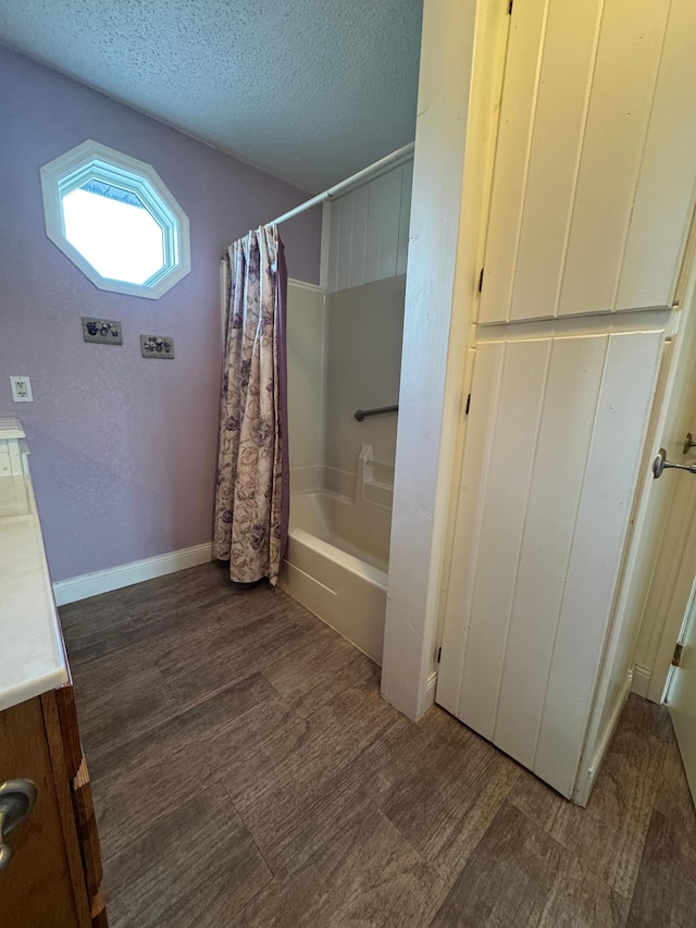 full bath featuring vanity, shower / bath combo with shower curtain, baseboards, a textured ceiling, and wood finished floors