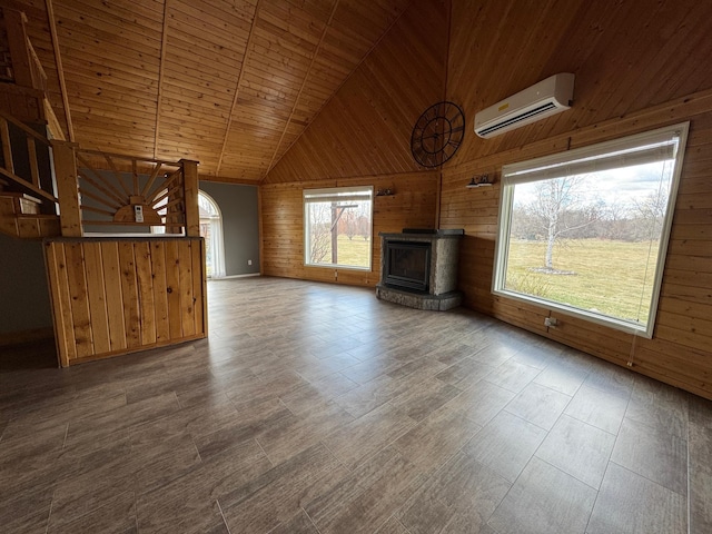 unfurnished living room with wooden walls, an AC wall unit, high vaulted ceiling, and wood ceiling