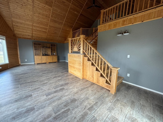 unfurnished living room with wooden ceiling, stairway, high vaulted ceiling, baseboards, and wood finished floors