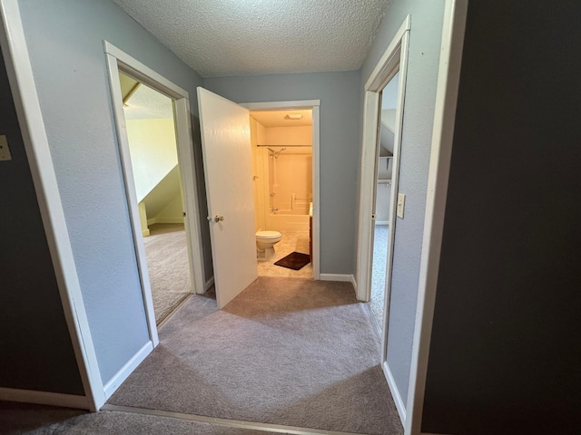 corridor with a textured ceiling and carpet floors