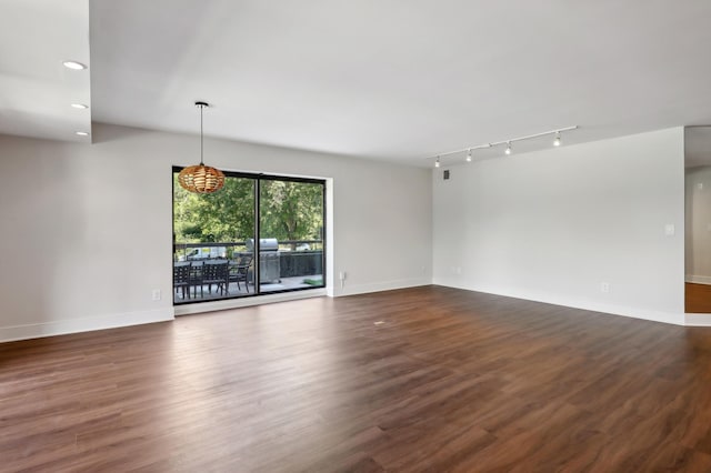 unfurnished living room with dark hardwood / wood-style flooring and rail lighting