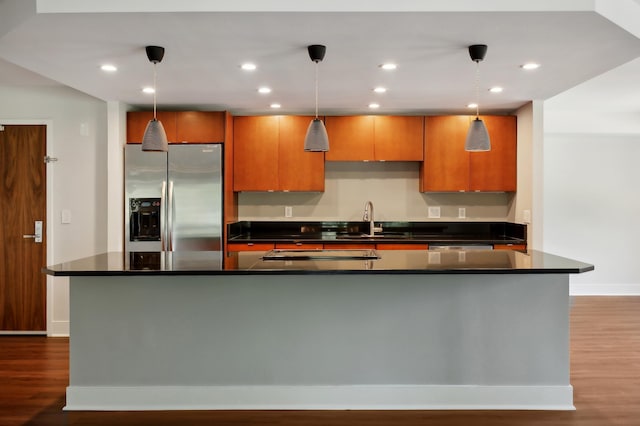 kitchen featuring pendant lighting, a kitchen island with sink, and stainless steel fridge with ice dispenser