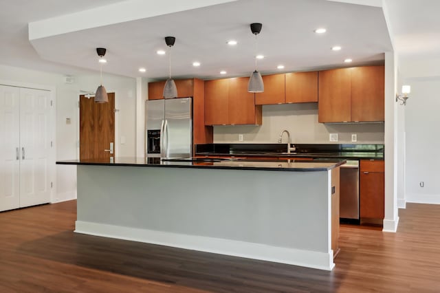 kitchen featuring pendant lighting, sink, dark wood-type flooring, a kitchen island with sink, and stainless steel appliances