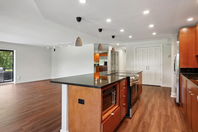 kitchen with stainless steel appliances, a center island, dark wood-type flooring, and decorative light fixtures