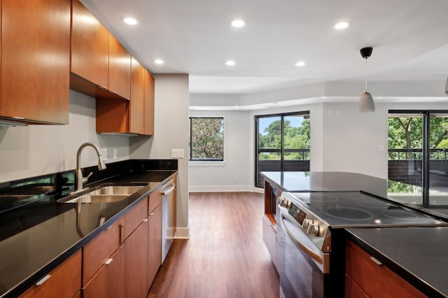 kitchen with stainless steel appliances, hanging light fixtures, sink, and dark hardwood / wood-style floors