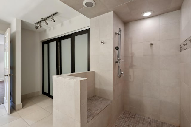 bathroom featuring tile patterned flooring, rail lighting, and tiled shower