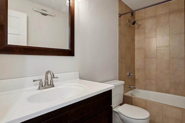 full bathroom with tiled shower / bath, vanity, and toilet