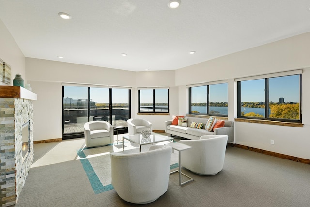 living room with a water view, light colored carpet, and a fireplace