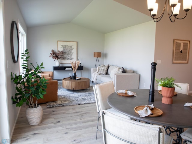 dining area with vaulted ceiling, an inviting chandelier, and light hardwood / wood-style flooring