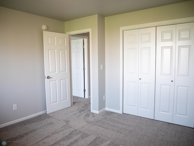 unfurnished bedroom featuring light colored carpet and a closet