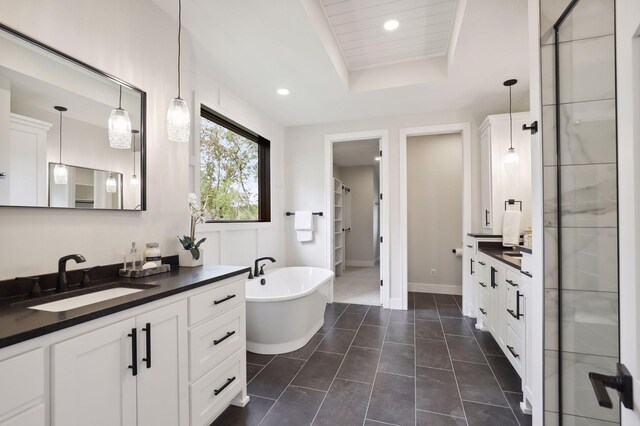 bathroom featuring plus walk in shower, vanity, tile patterned flooring, and a raised ceiling