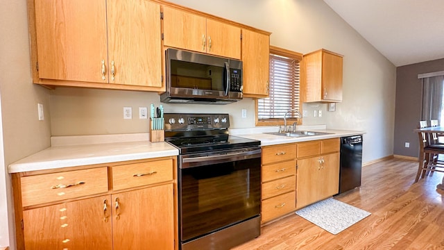 kitchen featuring black appliances, sink, light wood-type flooring, and vaulted ceiling