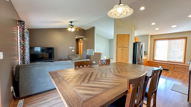 dining room with vaulted ceiling, light hardwood / wood-style flooring, a textured ceiling, and ceiling fan