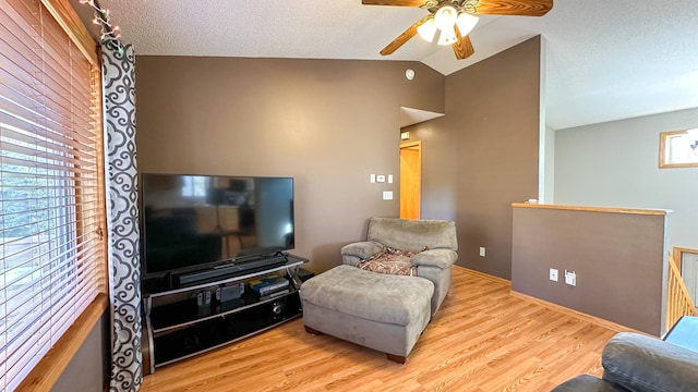 living room featuring light hardwood / wood-style flooring, lofted ceiling, a textured ceiling, and ceiling fan