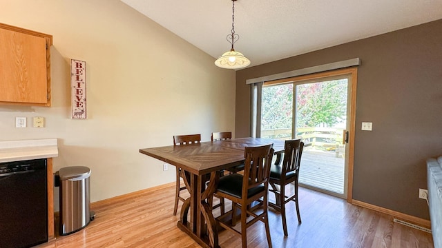 dining area with light hardwood / wood-style floors and vaulted ceiling