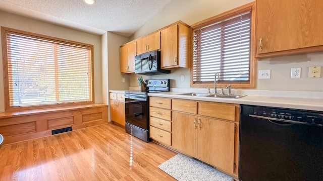 kitchen with sink, black appliances, vaulted ceiling, light wood-type flooring, and a textured ceiling