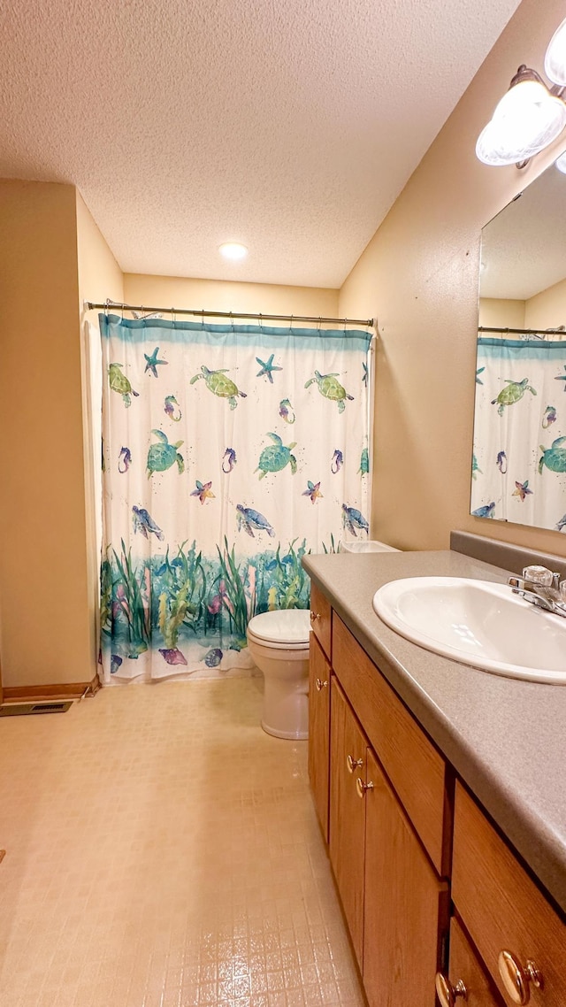 bathroom featuring vanity, toilet, a textured ceiling, and a shower with shower curtain