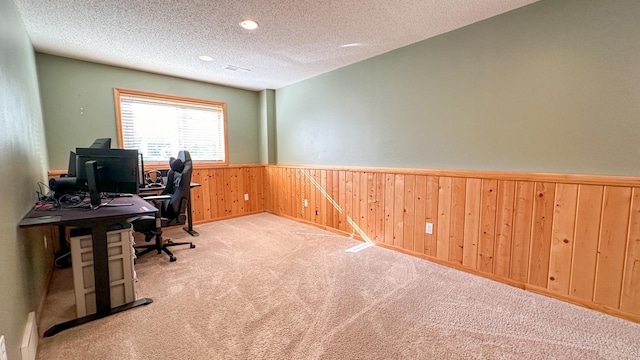 office space featuring light carpet, wood walls, and a textured ceiling