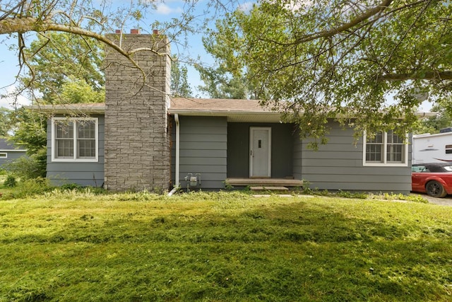 single story home featuring a chimney, a front lawn, and a shingled roof