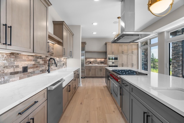 kitchen featuring sink, tasteful backsplash, light hardwood / wood-style flooring, island range hood, and appliances with stainless steel finishes