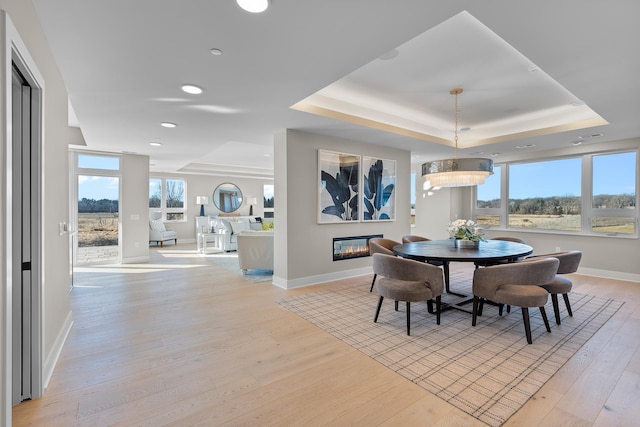 dining area featuring light wood-type flooring and a tray ceiling