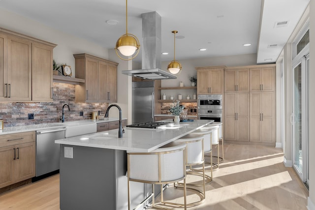 kitchen featuring pendant lighting, sink, appliances with stainless steel finishes, an island with sink, and island exhaust hood