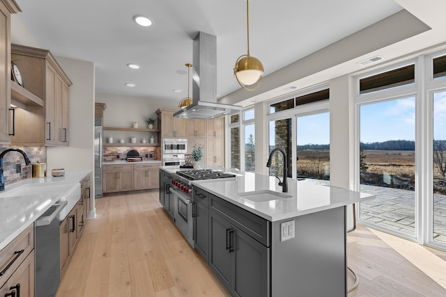 kitchen featuring sink, island range hood, decorative light fixtures, a center island with sink, and high quality appliances