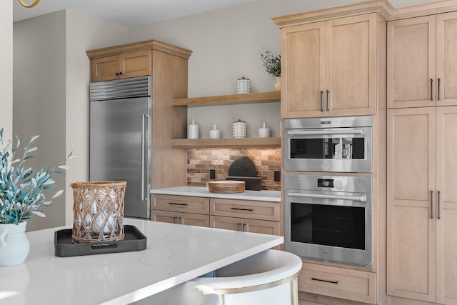 kitchen featuring stainless steel appliances, light stone countertops, a breakfast bar, and light brown cabinets