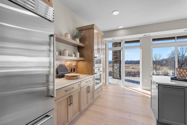 kitchen featuring stainless steel built in fridge, light brown cabinets, and light wood-type flooring