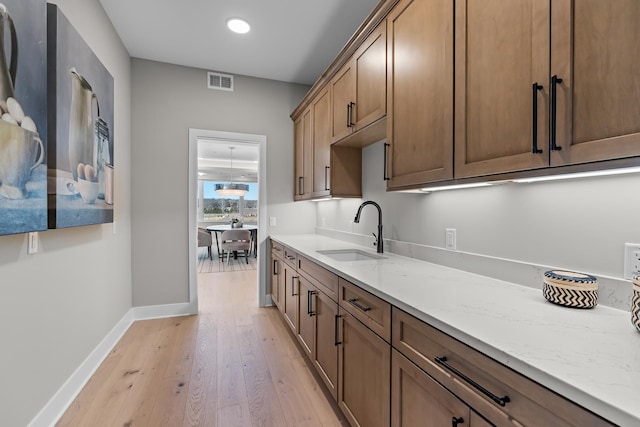 kitchen featuring light stone countertops, sink, and light wood-type flooring