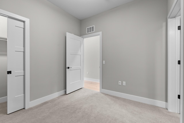 unfurnished bedroom featuring light colored carpet and a closet