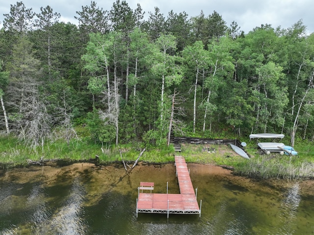 view of dock with a wooded view and a water view