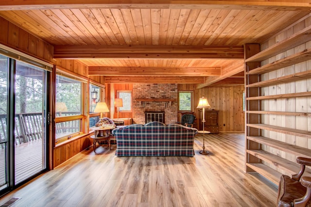 living area featuring wood finished floors, wooden walls, beam ceiling, and visible vents