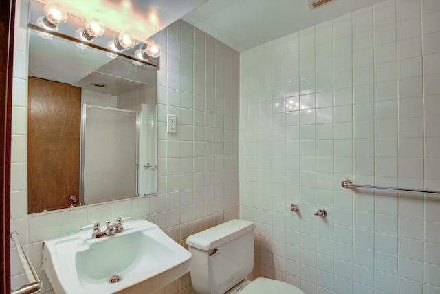 full bathroom featuring a shower with door, tile walls, a sink, and toilet