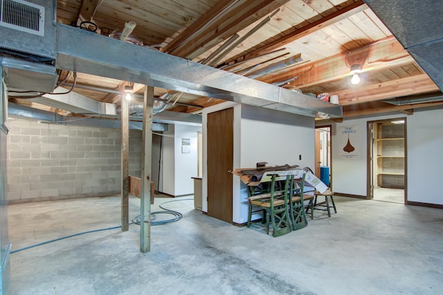 unfinished basement featuring visible vents, baseboards, and concrete block wall