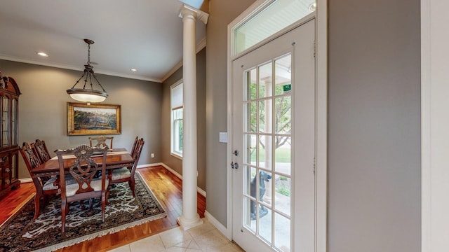 dining room with ornate columns, light wood-type flooring, and crown molding