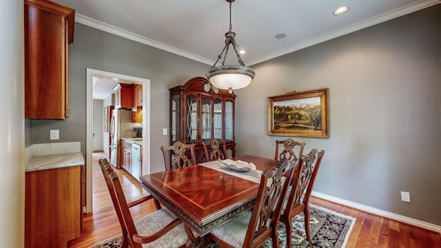 dining area with light wood-type flooring and ornamental molding