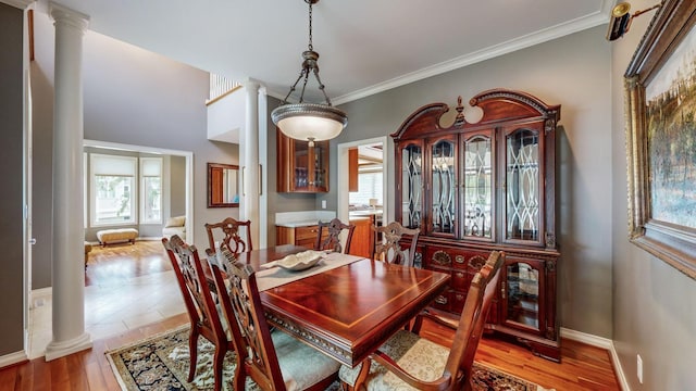 dining space with ornamental molding, hardwood / wood-style flooring, and decorative columns