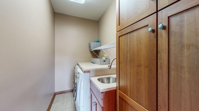 laundry area with washing machine and dryer, cabinets, and sink