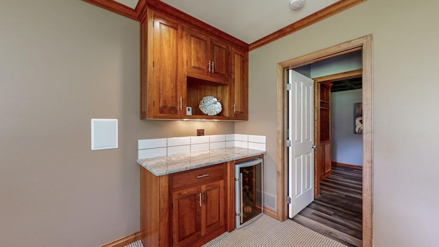 kitchen with beverage cooler, light stone counters, light hardwood / wood-style floors, and crown molding