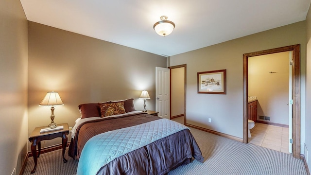 bedroom featuring ensuite bathroom and light carpet