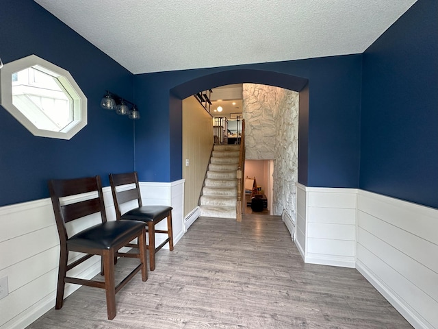 interior space featuring baseboard heating, a textured ceiling, and hardwood / wood-style floors