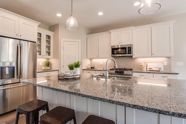 kitchen featuring appliances with stainless steel finishes, white cabinetry, hanging light fixtures, and sink